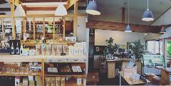 The image shows a cozy coffee shop in Karuizawa with shelves stocked with coffee products, and a seating area with wooden furniture and decorative plants.