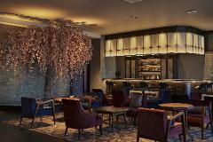 A sophisticated bar area features a large artificial cherry blossom tree, plush seating, and a well-stocked bar.