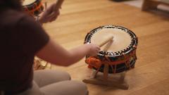 Mukojima Geisha Experience: Training Session & Ozashiki Banquet at a Ryotei Restaurant A person is playing a Japanese drum with drumsticks during a training session.