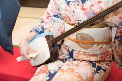 Play a Traditional Japanese String Instrument -- "Shamisen" A person in a colorful kimono plays a shamisen, a traditional Japanese three-stringed lute.