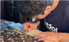 Experience 200 Years of Craftsmanship: Wajima Lacquerware Studio Tour (Visit a craftsman's home) A craftsman carves a wooden object in a studio filled with wood shavings.