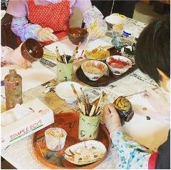 Lacquer Painting Experience Plan Participants in a lacquer painting workshop paint various objects with colorful paints and brushes.