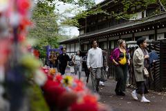 Meisatsu Zojoji Temple - A Journey to Tokyo’s Cultural Origins A group of people walk past a traditional Japanese building with a purple torii gate and colorful flowers in the foreground.