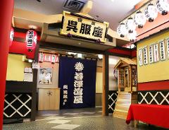 This is an indoor shot of a Japanese restaurant entrance featuring traditional decor like lanterns, a wooden sign with calligraphy, and a blue curtain.