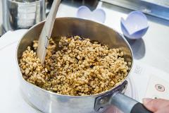 A close-up shot shows a wooden spatula stirring puffed rice coated in caramel in a metal pot.