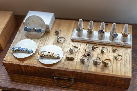 Ceramică și porțelan: Povești ale artizanilor din spatele meșteșugului A pale blue, elegantly twisted ceramic vase sits on a rustic wooden stool in a dimly lit studio, surrounded by blurred elements hinting at a craftsperson's workspace.