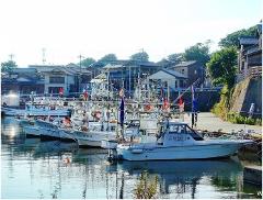 Fishing boats are docked in a tranquil harbor in the Japanese fishing town of Hashitate.