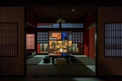 A serene Japanese room opens to a tranquil garden at dusk, illuminated by warm lighting.