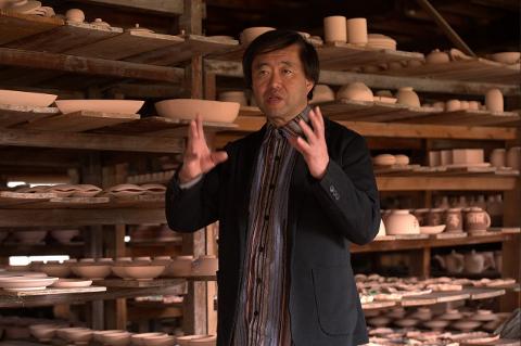 Ceramică și porțelan: Povești ale artizanilor din spatele meșteșugului An artisan presents a white ceramic bowl to a group of onlookers.