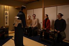 Daimyo Diary – Stroll with an Expert Guide at "Kenroku-tei" & Experience Traditional Tea Ceremony (With Breakfast) A group of people participates in a traditional Japanese tea ceremony, with one person in a kimono serving others seated at low tables.