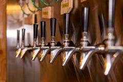 A row of gleaming, stainless steel beer taps with black handles stands ready to pour refreshing beverages, offering a glimpse into Hakodate's bar scene.