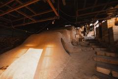 Pottery & Porcelain: Stories of the Artisans Behind the Craft This image depicts an old kiln with a distinctive earthy, undulating surface, possibly for firing pottery.