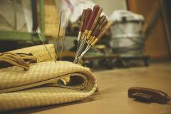 A close-up shot shows tatami-making tools, including needles and awls, resting on folded tatami mats, hinting at the detailed artistry involved in traditional tatami creation.
