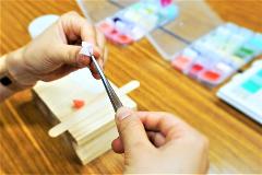 Traditional Japanese Craft Experience -- "Tsumami-Zaiku" Accessory A person is carefully holding a piece of fabric with tweezers, preparing to create a traditional Japanese Tsumami-Zaiku accessory.
