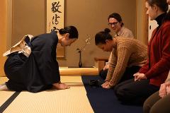 Daimyo Diary – Stroll with an Expert Guide at "Kenroku-tei" & Experience Traditional Tea Ceremony (With Breakfast) A group of people participate in a traditional tea ceremony, bowing respectfully on tatami mats.