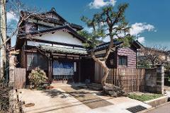 A traditional Japanese building with a pine tree in front is featured in an image from a tour of Kanazawa Geigi culture.