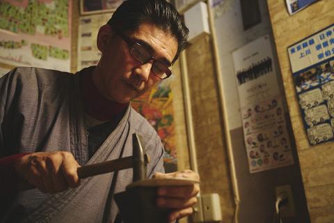 A Japanese craftsman hammers a silver bookmark in his workshop.