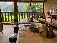 Lacquer Painting Experience Plan Two tables in an art studio are set up for lacquer painting with brushes and bowls of paint, overlooking a lush green landscape.