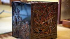 Visit Nikko's Craftsmanship Workshop to Experience Historic Techniques A close-up shot shows an ornate, dark wooden box with carved floral motifs and three drawers.
