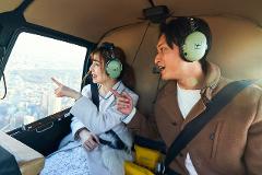 Private Helicopter Tour of Tokyo A man and a woman in a helicopter, wearing headsets, look out the window at the city below.