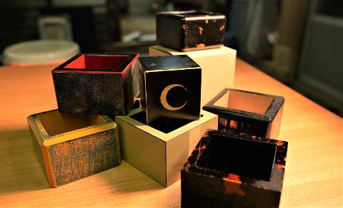 Inuyama Morning Tour: Shark Skin Masu Cup Crafting Class A collection of small, decorative square boxes with intricate patterns and designs are arranged on a wooden table.