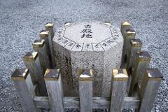 Ise/ Rental Electric Scooter~sacred river route~/90min An octagonal stone marker engraved with Japanese characters sits on a bed of gravel, surrounded by a wooden fence with gold-capped posts.