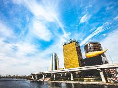 Tokyo Asakusa Half Day Walking Tour with Local Guide A bright blue sky with wispy clouds hangs over a golden skyscraper, a modern apartment building, and a prominent golden sculpture.
