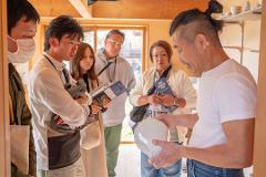 Pottery & Porcelain: Stories of the Artisans Behind the Craft An artisan presents a white ceramic bowl to a group of onlookers.
