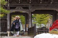 A monk in traditional attire walks across a bridge at Sojiji Temple, a historic Japanese Buddhist temple.