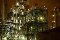 Certainly! Here's a description of the image within the character limit:The image depicts a brightly lit, complex industrial plant at night, featuring interconnected structures, pipes, and towers, conveying an atmosphere of intense activity.