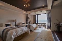 A hotel room with two beds and a large window overlooking a lake.