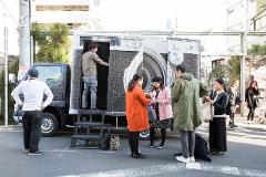 "Reborn-Art" Tour: Experience Contemporary Art on the Oshika Peninsula People gather near a truck painted with a giant camera graphic on the Oshika Peninsula.