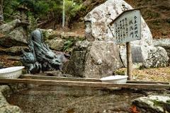 A stone dragon sculpture spouts water into a basin at a Japanese shrine.