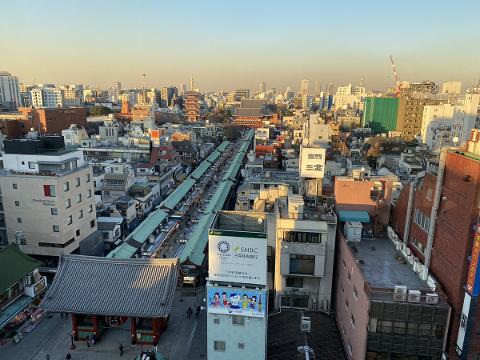 A panoramic view of Tokyo's Asakusa district, featuring traditional temples, bustling market streets, and modern cityscapes under a clear sky.