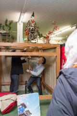 Two men operate a traditional Japanese puppet from a wooden frame, with a detailed puppet adorned in an elaborate kimono suspended above them.