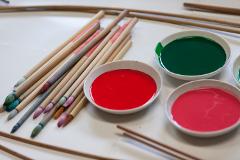 A collection of traditional Japanese calligraphy brushes lies beside small bowls filled with red and green dyes.