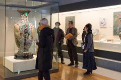 A group of people admire a large, ornate vase displayed in a museum exhibit.