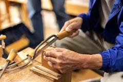 Experience the Craftsmanship of the Oroku Comb born in Kiso A woodworker meticulously uses a fine-toothed saw to shape a piece of wood.