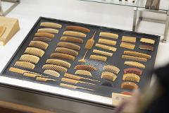 Experience the Craftsmanship of the Oroku Comb born in Kiso A curated display of various wooden combs, showcasing different sizes, shapes, and tooth spacing, are laid out on a black tray.