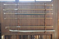 A wooden wall with various poles and sticks mounted on it.