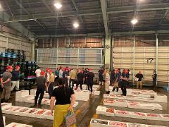 People in a warehouse with many crates of fish, likely at an auction.