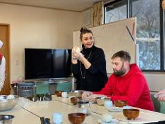 A group of people are gathered around a table, preparing to make onigiri (rice balls).