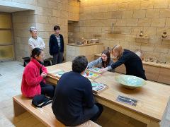 People at a table are engaged in a pottery experience with sake tasting.