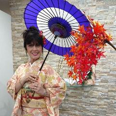 Learn Nagoya Yuzen Dyeing and Have a Kimono Dressing Experience in a Luxurious Traditional Japanese Restaurant A woman in a kimono holds a Japanese umbrella and a branch of red leaves.