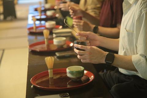 Discover the Art of Yamanaka Lacquerware & Experience the Ultimate Hospitality of the Tea Ceremony People participate in a tea ceremony, with close-ups on their hands holding tea bowls and whisks.