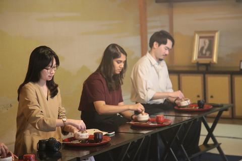 Discover the Art of Yamanaka Lacquerware & Experience the Ultimate Hospitality of the Tea Ceremony Three individuals participate in a tea ceremony, preparing matcha in a traditional setting.