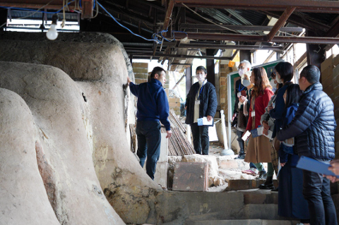 Fukushima 2-Day Cultural Escape: Aizu Hongo-yaki Pottery Tour A group of people stand on stairs at an open studio tour in front of a large clay kiln at Aizu Hongo-yaki.