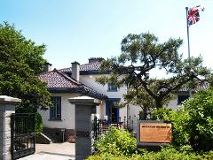 A photograph captures the historic Old British Consulate in Hakodate, Japan, with its distinctive architecture and a British flag proudly displayed.