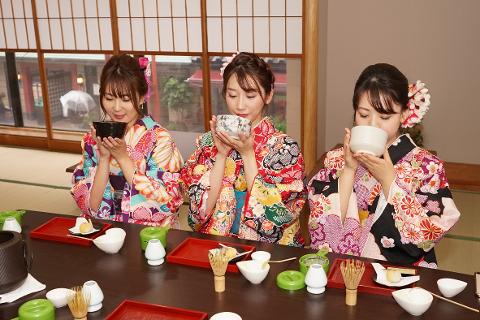 Three women in colorful kimonos enjoy a tea ceremony, each holding a bowl of matcha.