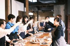 A group of women, wearing aprons and gloves, are gathered around a wooden table, holding up and examining fish.